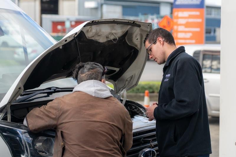 Two people inspecting the engine bay of a used ute
